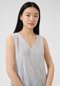 Lightweight, sleeveless top featuring a V-neck, made of a soft fabric with vertical gray and white stripes. Simple design with minimal detailing.