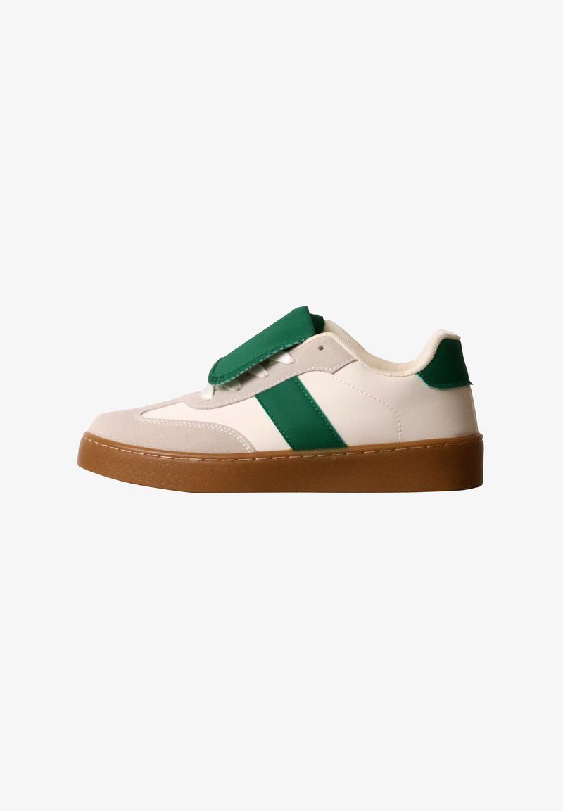 Baskets blanches avec des accents verts et une semelle marron, avec un grand rabat vert couvrant les lacets sur fond blanc.
