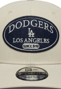 Beige Basecap mit einem navyblauen gestickten Patch. "Dodgers," "LA" und "Los Angeles seit 1938" deutlich sichtbar. Verstellbarer Riemen.
