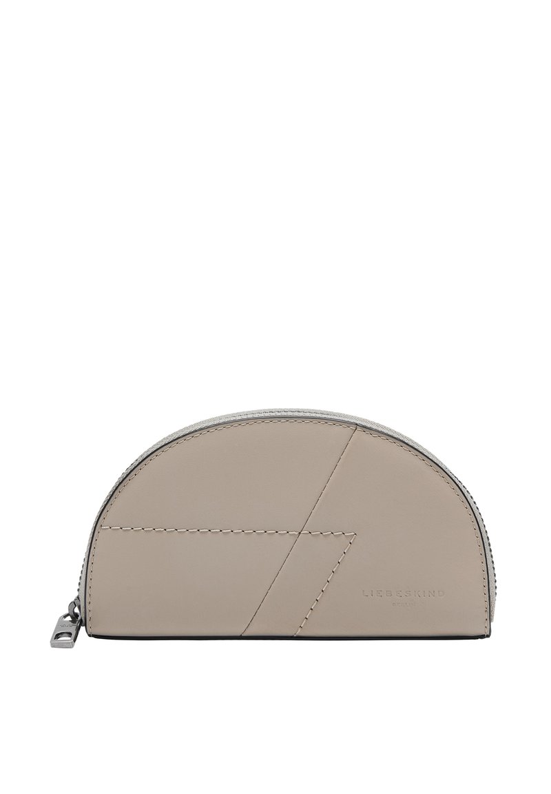 Cartera de cuero en un beige claro con forma redondeada. Presenta costuras geométricas en contraste y un cierre de cremallera con tirador de metal.
