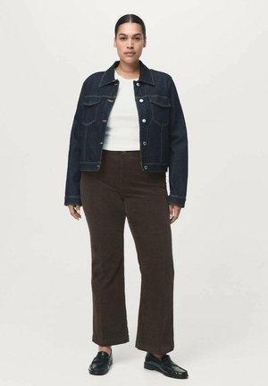 Veste en denim bleu foncé avec deux poches poitrine, boutons argentés ; assortie à un pantalon en velours côtelé marron et des chaussures noires, présentant une coupe droite.