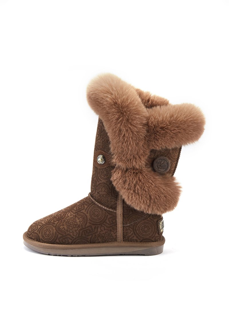 Brązowe buty z futrzanym wykończeniem, ozdobione misternym wzorem na zewnątrz, z szerokim futrzanym mankietem i dekoracyjnym guzikiem z boku. Płaska gumowa podeszwa.