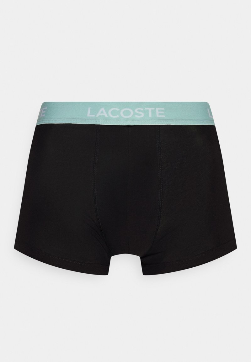 Zwarte boxershorts met een lichtblauwe elastische tailleband met het "LACOSTE" logo. Glad materiaal met een strakke pasvorm en minimale stikseldetails.