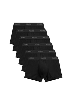 Atletyczny mężczyzna z krótkimi włosami, ubrany w czarne bokserki z pasem "Atlantic", stojący na jednolitym jasnoszarym tle.