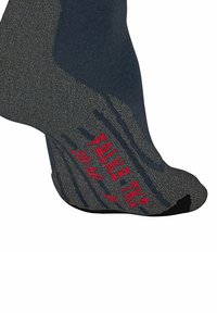 Chaussette noire et grise avec talon et pointe renforcés. "FALKE TZN" est imprimé en rouge sur la semelle. Tissu texturé pour une meilleure adhérence.