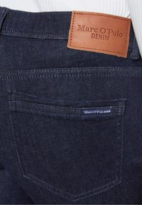 Tmavě modré džíny z denimu s koženým štítkem s embosovaným nápisem "Marc O'Polo DENIM" a zadní kapsou se šitým značkovým štítkem.