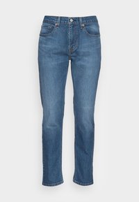 Jeans unisex de pierna recta en denim azul medio. Diseño clásico de cinco bolsillos, costuras visibles y cierre de botón metálico.