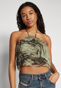 Top halter scurt dintr-un material verde translucid cu modele abstracte negre. Are un accent decorativ central și bretele subțiri.