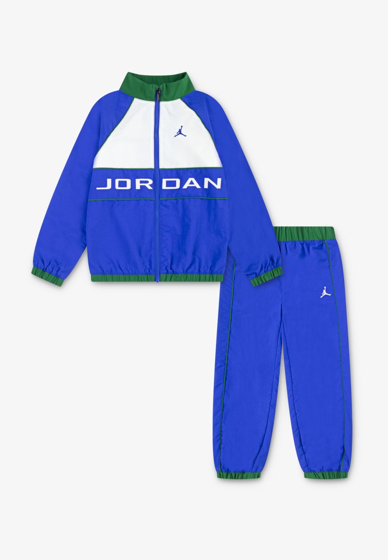 Zils sporta uzvalks, kas izgatavots no viegla materiāla. Jakai ir baltas un zaļas akcenti ar "JORDAN" uzrakstu; biksēm ir elastīgas aproces un logo.