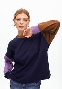 Sweter w blokach kolorystycznych w odcieniach granatowym, brązowym i lawendowym, z prążkowanymi mankietami i okrągłym dekoltem; wykonany z miękkiej, teksturowanej tkaniny.