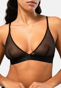 Musta läpinäkyvä bralette kolmion muotoisilla kupeilla, säädettävillä hihnoilla ja sileällä, joustavalla vyötäröillä. Minimalistinen muotoilu, ilman toppauksia.