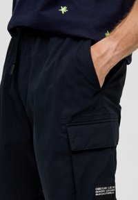 Granatowe szorty cargo z boczną kieszenią, elastycznym pasem i sznurkiem. Oznaczone etykietą z napisem "CABO SAN LUCAS". Gładka tekstura.