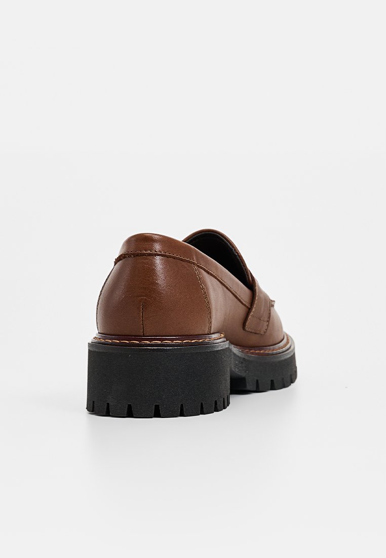 Braune Leder-Slipper mit Blockabsatz und strukturiertem schwarzen Gummisohle, die ein einfaches Design und kontrastierende Nähte aufweisen.