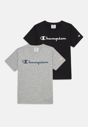 Két rövid ujjú Champion logós póló, az egyik fekete fehér felirattal, a másik szürke tengerészkék felirattal, fehér háttéren lefektetve.