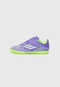 Chaussure de sport violette avec une semelle vert fluo, dotée d'une sangle auto-agrippante, d'une tige texturée et de rayures blanches diagonales pour le détail du design.