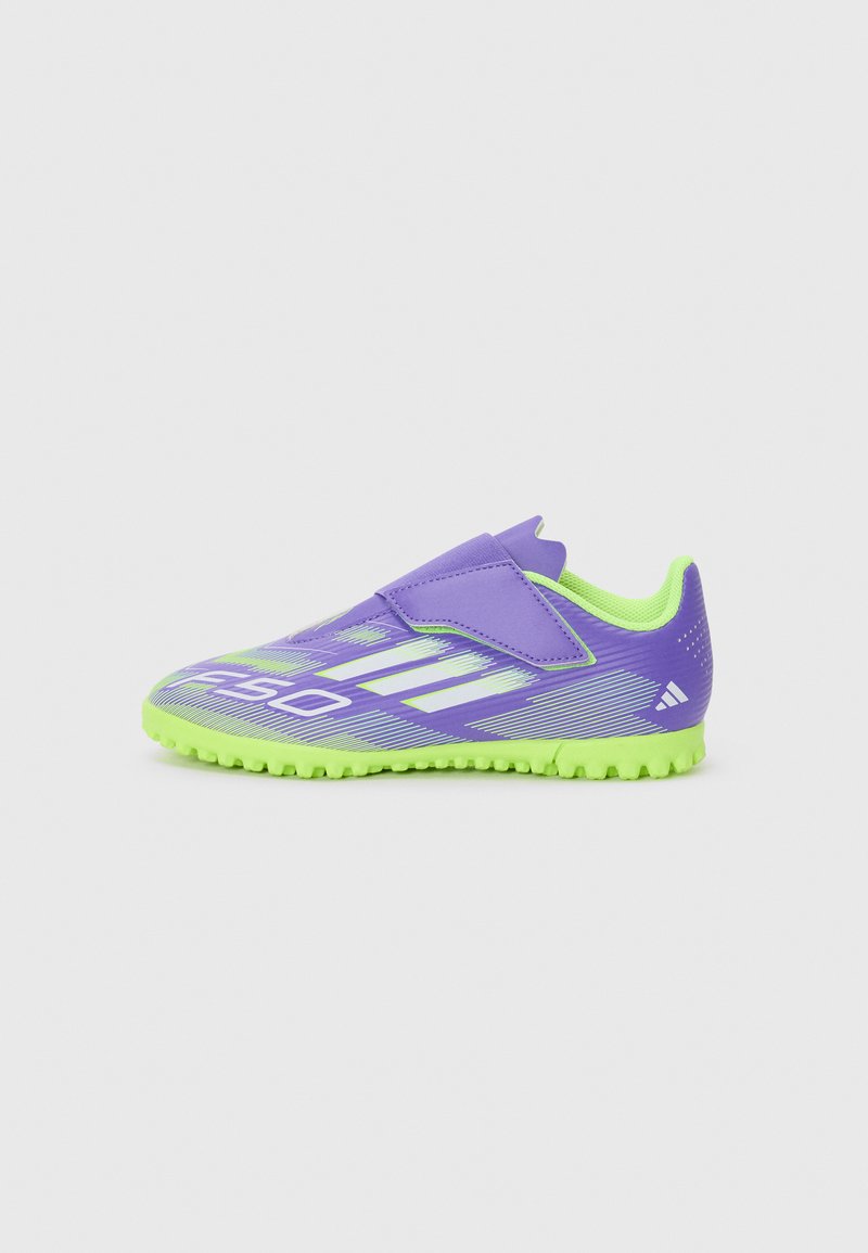 Chaussure de sport violette avec une semelle vert fluo, dotée d'une sangle auto-agrippante, d'une tige texturée et de rayures blanches diagonales pour le détail du design.