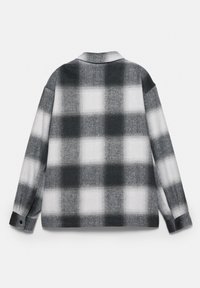 Cămașă cu mânecă lungă, în carouri alb-negru, cu guler clasic și manșete cu nasturi, realizată dintr-un material moale.