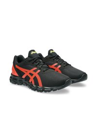 Scarpe da ginnastica nere con accenti rossi e una tomaia in rete. Presentano una suola testurizzata e un tallone rinforzato per il supporto. Design con lacci.