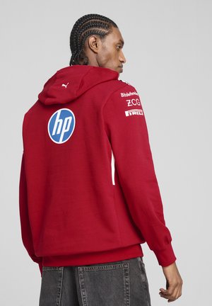 Hanorac roșu cu glugă din bumbac, având accente albe și un logo mare HP albastru pe spate. Mansete și tiv ribbate.