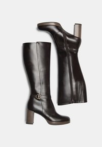 Black leather knee-high boots with a chunky heel, buckle detail, and zipper closure on the side. Smooth texture with stitching accents.