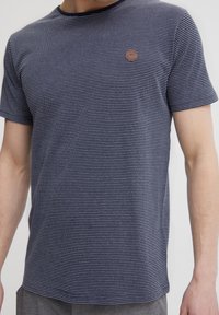 Navy blue striped short-sleeve t-shirt made from soft fabric, featuring a round neckline and a small contrasting logo on the left chest.