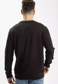 Czarna bluza z długimi rękawami, okrągłym dekoltem i prążkowanym wykończeniem. Wykonana z teksturowanej tkaniny o gładkim wykończeniu.