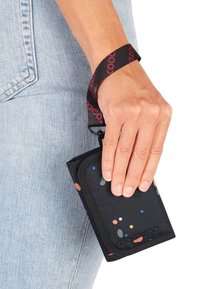 Black fabric wallet featuring colorful speckles, secured with a wrist strap. Compact design with a zip closure and textured surface.