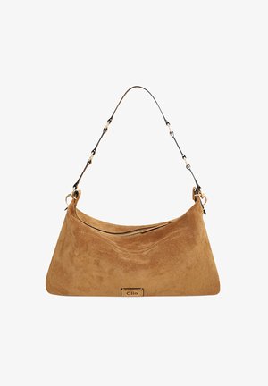 Sac à main en daim marron avec une forme incurvée, fermeture éclair et anse ornée d'une chaîne. Dispose d'une petite plaque logo à l'avant.