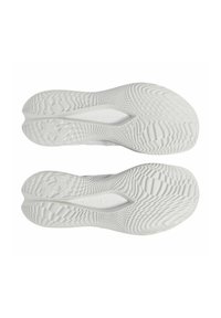 Le suole delle scarpe sportive bianche presentano una superficie in gomma testurizzata con un motivo a zigzag e un marchio. Il design del battistrada migliora la presa e la stabilità.