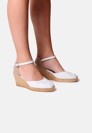 Espadrilles blanches en toile à talon compensé avec une semelle en jute tressé et une sangle de cheville. Bout rond et détail texturé au niveau du talon. Idéal pour une tenue décontractée.