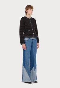 Quiltet sort jakke med rund hals, sølvfarger på knappene og to frontlommer. Vide denim-bukser med kontrasterende blå og lyseblå paneler.