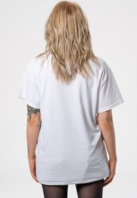 White cotton t-shirt with short sleeves and a relaxed fit, viewed from the back. Smooth texture, simple design, no visible logos or embellishments.