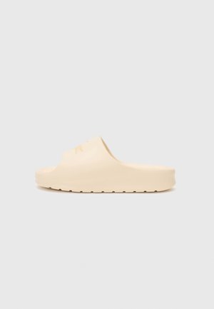 Beige slip-on gummisandal med formstøbt fodseng og tekstureret ydresål, vist fra siden på neutral baggrund.