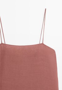 Spaghetti-strap roze linnen top met rechte halslijn en gestructureerde stof op een witte achtergrond.