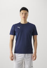 Marineblå treningstopp laget av pustende materiale, med kortermede ermer og en hvit Puma-logo på brystet. Slim fit-design.