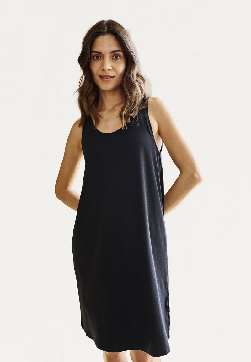 Vestido negro sin mangas hecho de una tela suave, con un corte holgado, cuello redondo y botones laterales como detalle. Diseño simple y casual.