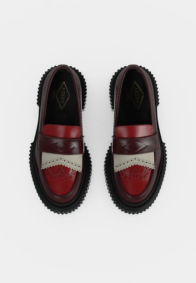 Ζευγάρι γυαλιστερά δερμάτινα loafers σε μπορντό, κόκκινο και μπεζ με διακοσμητικές λεπτομέρειες brogue και παχύ μαύρο οδοντωτό πέλμα, από ψηλά.