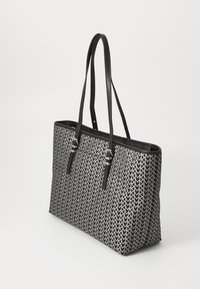 Black and white tote bag with arrow pattern, featuring a structured shape, two long handles, and silver hardware accents.