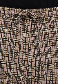 Housut värikkäillä kuoseilla, joissa on beige, vaaleanpunainen ja musta ruutukuvio kukkakoristeilla, joustava vyötärö ja sidottava nauha.