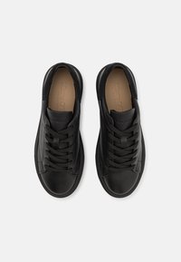 Sneakers neri in pelle liscia con un accento in suede testurizzato e punta tonda. Presentano lacci piatti e colletto imbottito per il comfort.