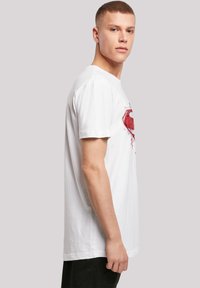 White cotton t-shirt featuring a red graphic design on the chest. Short sleeves and a crew neck, showcasing a relaxed fit.