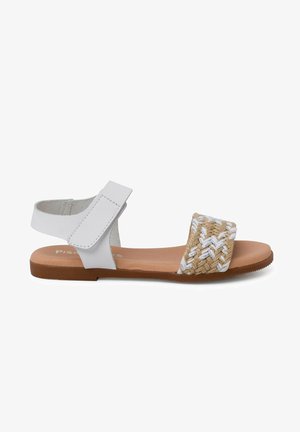 Sandale à lanières blanches en cuir, dotée d'une bande en fibres naturelles tissées avec des accents blancs et d'une semelle plate en caoutchouc brun. Design minimaliste.