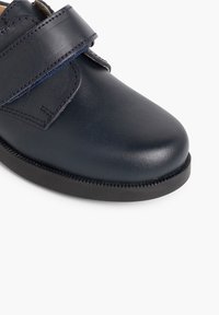 Tumši zilas ādas kurpes ar gludu virsmu, ar velcro siksnu un melnu gumijas zoli, ar smalkām šuvju akcentēm.
