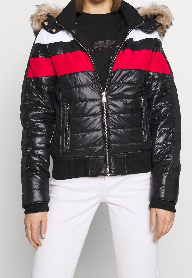 Puffjacka med svarta, röda och vita paneler, med en faux fur-hette, dragkedja fram och ribbade ärmslut och fåll. Texturerad, glansig yta.