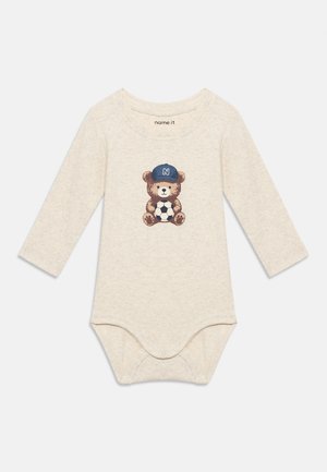 Body bébé à manches longues couleur crème avec un ourson portant une casquette bleue tenant un ballon de football imprimé sur la poitrine, fermetures pression en bas.