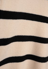 Beiger Strickstoff mit horizontalen schwarzen Streifen. Die Textur ist weich und hat ein geripptes Muster, das das kontrastierende Farbdessin betont.