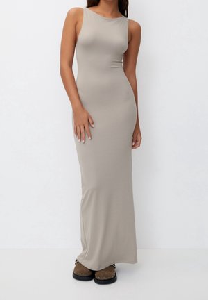 Long, form-fitting beige dress with a high neckline, made of smooth fabric. Features narrow shoulder straps and a floor-length silhouette.