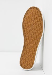 Rubber shoe sole with a brown textured pattern, white edges, and a size label "37" visible. Designed for traction and durability.