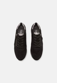 Černé semišové tenisky s hladkým šedým akcentem, s tkaničkami a detaily na bočním zipu. Zaoblená špička a polstrovaná podrážka.