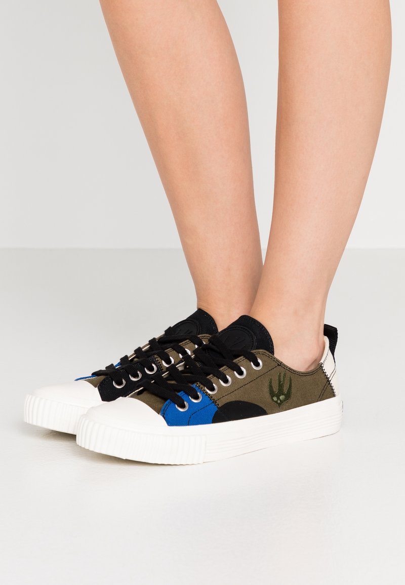 Canvas låga sneakers i olivgrön, svart och blå med vit gummisula, med rund tå och svarta snörningar. Broderad logotypdetalj.